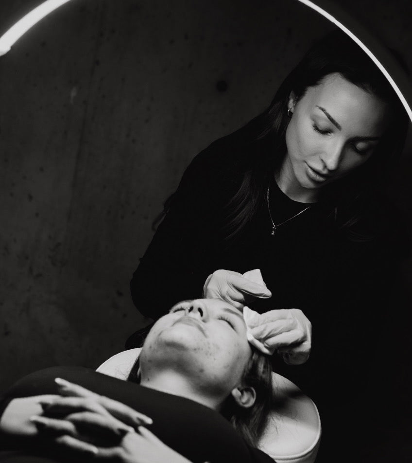 Black and white photo of a woman receiving a facial treatment from another woman.